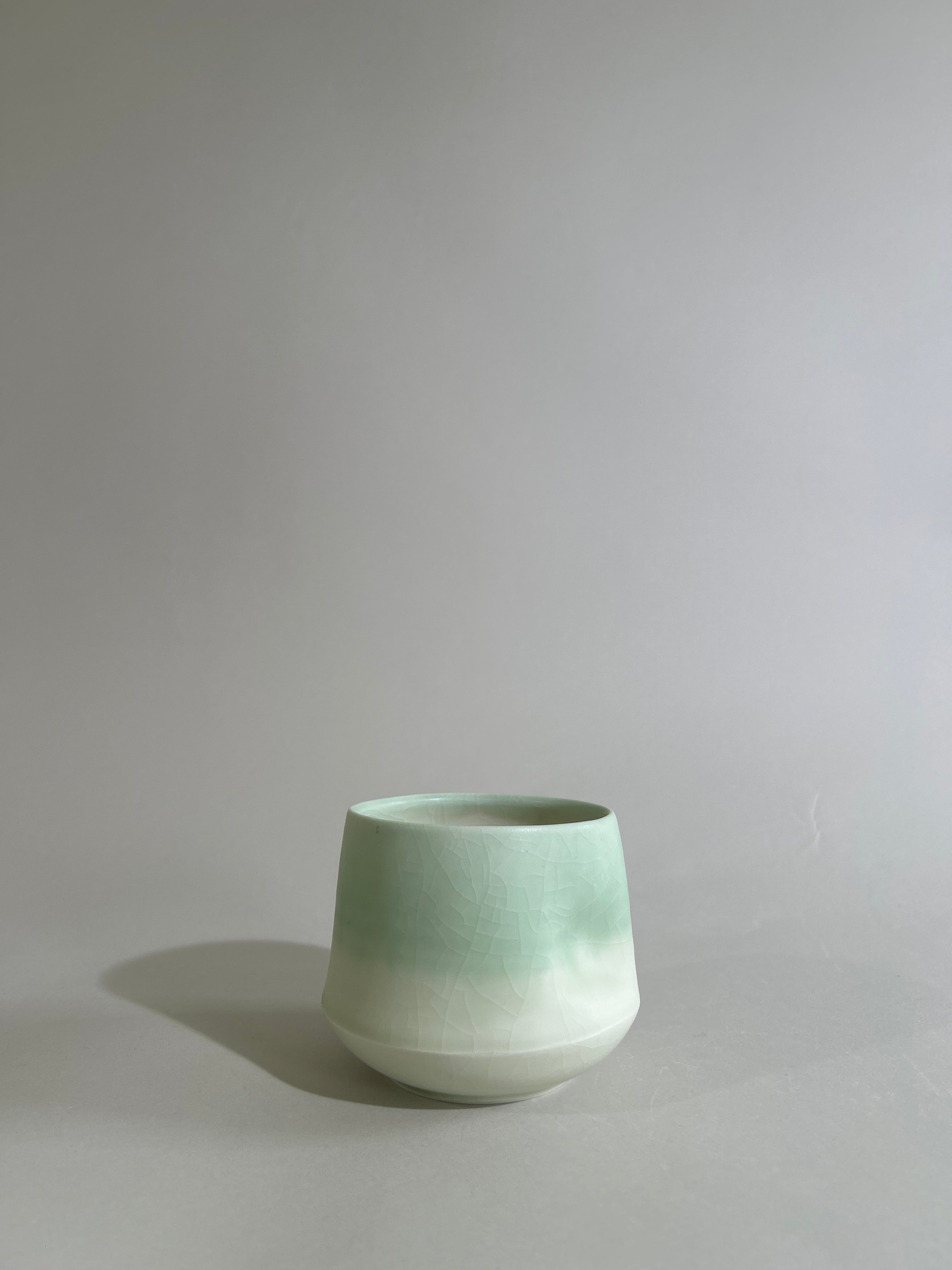 Pale green and white teabowl with a thumb dent in the side